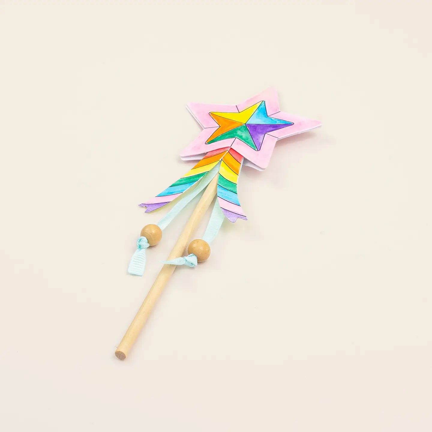Colorful star-shaped wand with a rainbow design on a light beige background