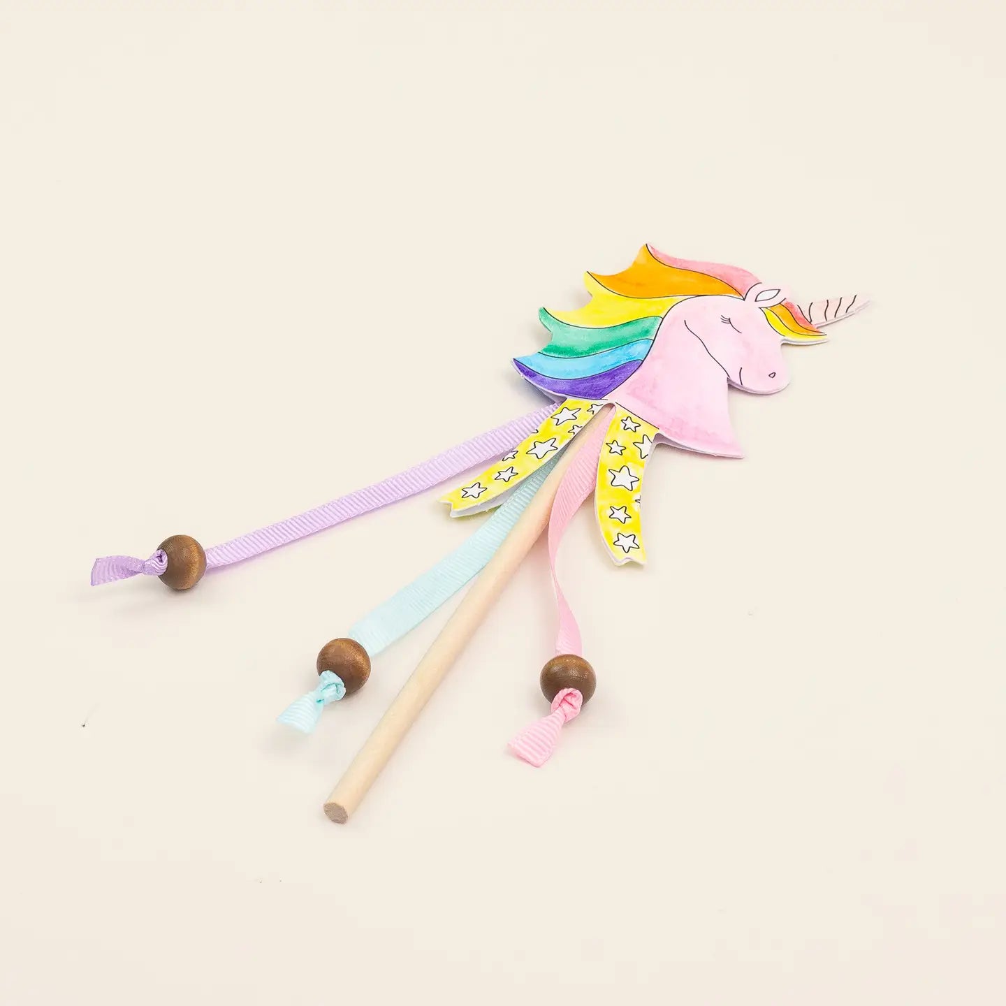 Colorful unicorn toy with wooden sticks on a light beige background