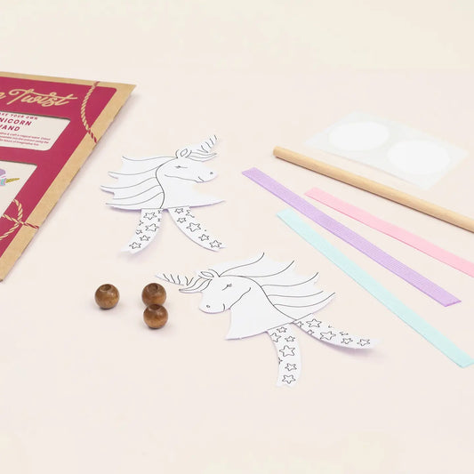 Unicorn-themed craft kit with coloring sheets, markers, and beads on a light surface.
