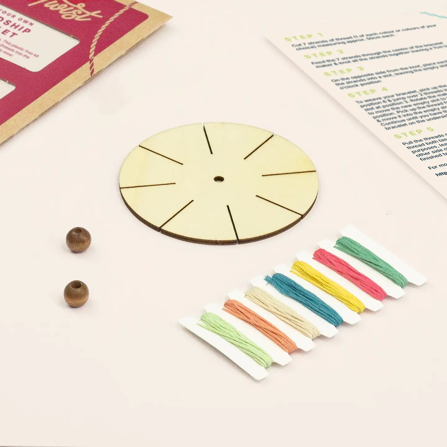 Wooden bracelet-making kit with beads and colorful strings on a light surface