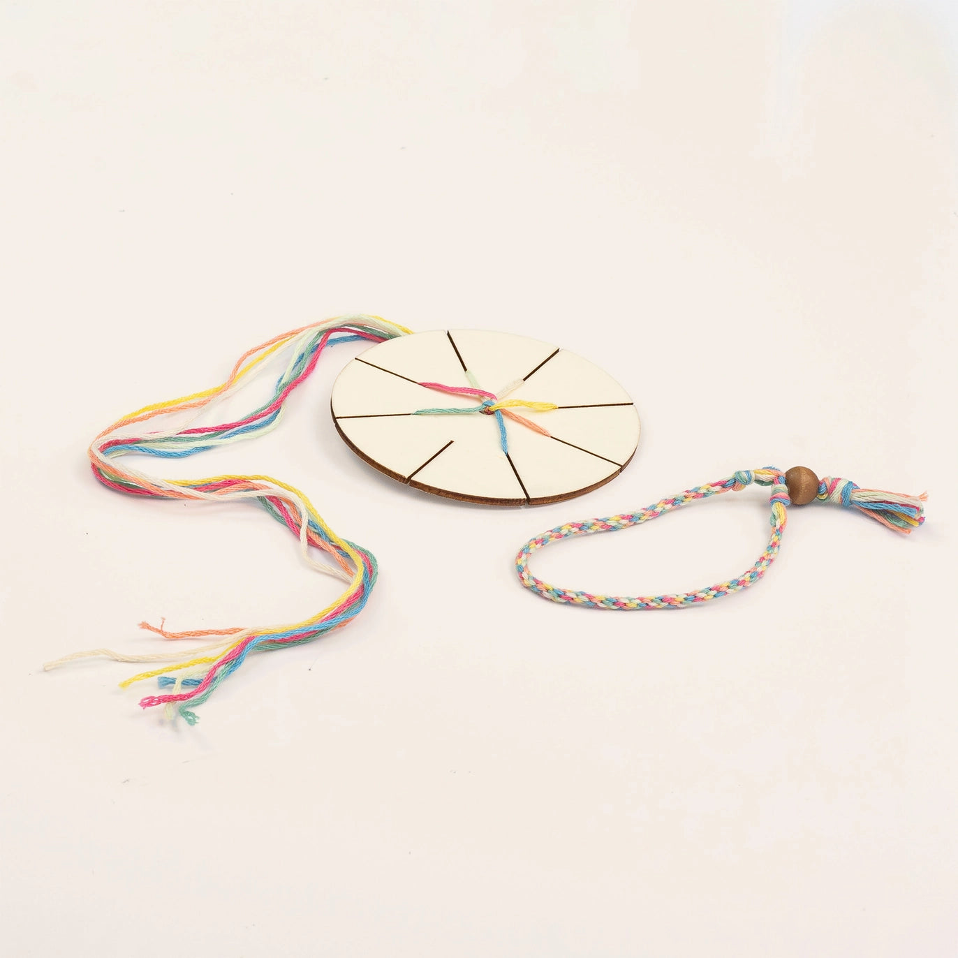 Colorful woven bracelet with a wooden disc and beads on a light background
