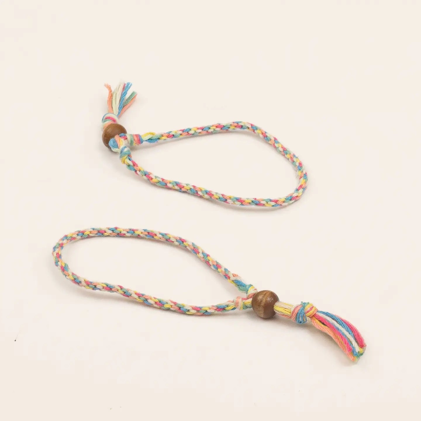 Colorful braided dog toy with wooden beads on a light beige background