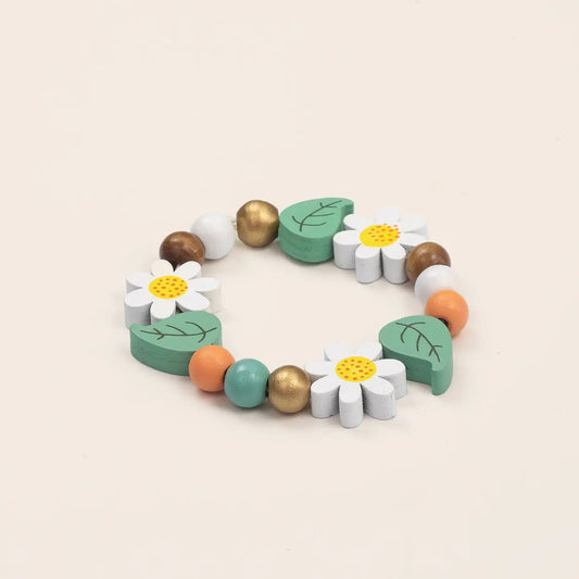 Colorful wooden bracelet with flowers and leaves on a beige background