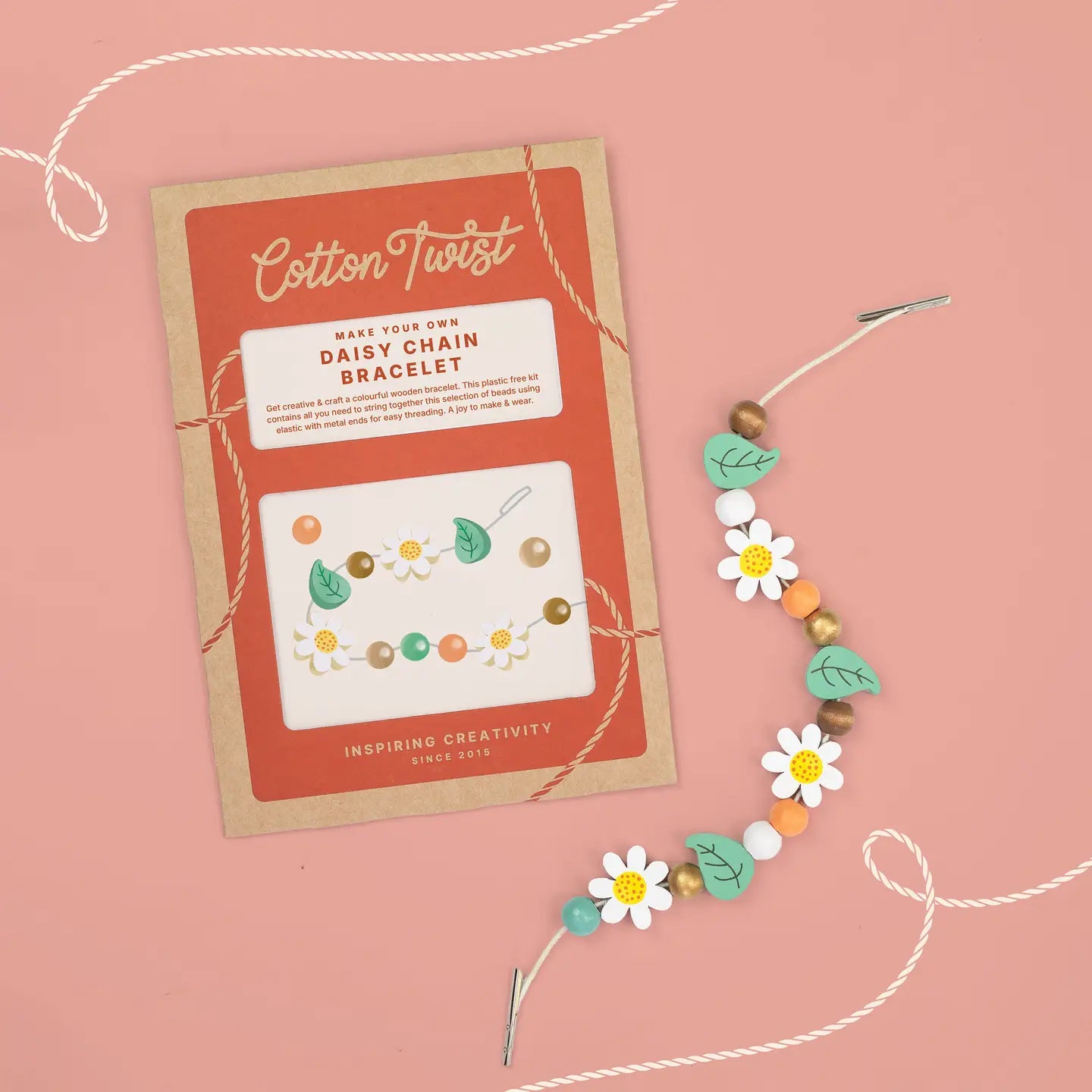 Cotton Twist daisy chain bracelet kit with a bracelet on a pink background